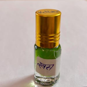 May include: A small glass bottle with a gold cap, containing a green liquid. The bottle has a white label with text in a foreign language. The cap is labelled "Vetiver".