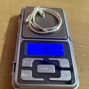 May include: A silver chain necklace on a digital scale displaying 9.2 grams.