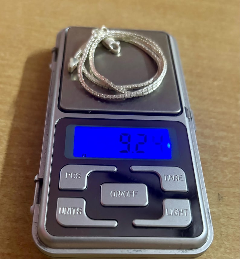 May include: A silver chain necklace on a digital scale displaying 9.2 grams.