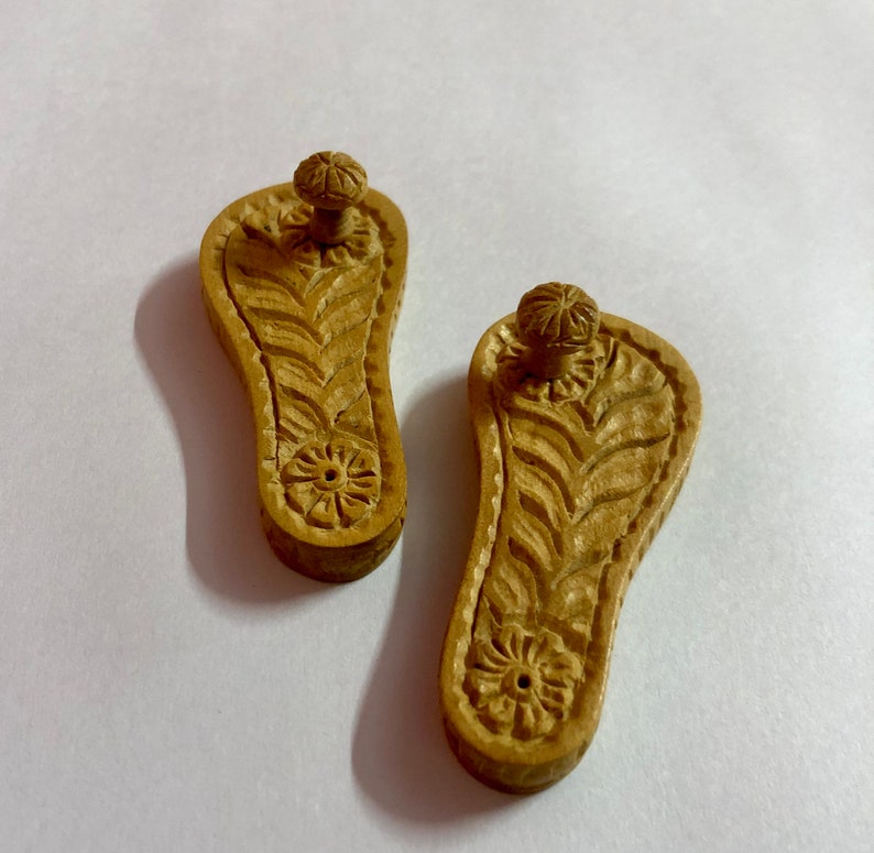 Pu&ograve; includere: Due porta incenso in legno a forma di piedi con intricate sculture. I porta incenso hanno un piccolo foro al centro del piede e una manopola nella parte superiore.