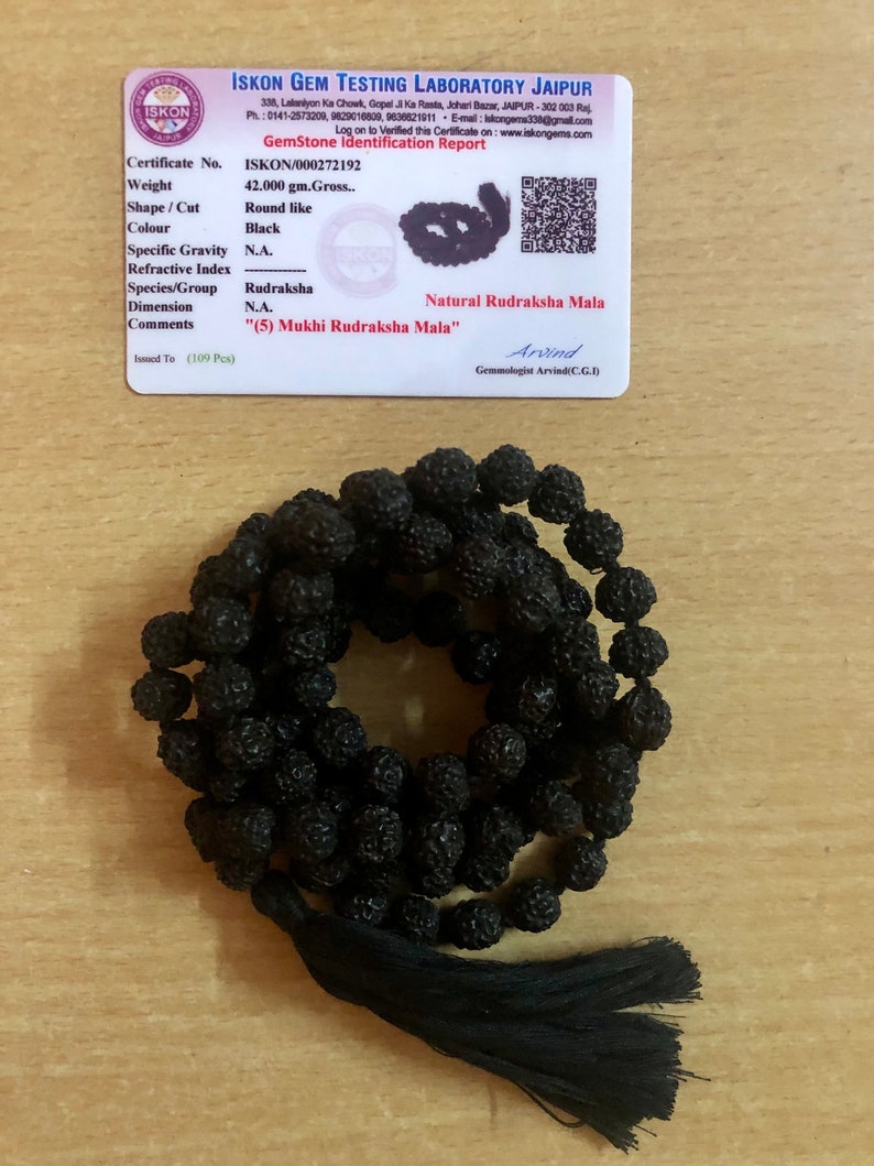 May include: A black Rudraksha Mala with a tassel. The mala is made of 109 beads and is 42 grams. The certificate states that it is a "(5) Mukhi Rudraksha Mala".