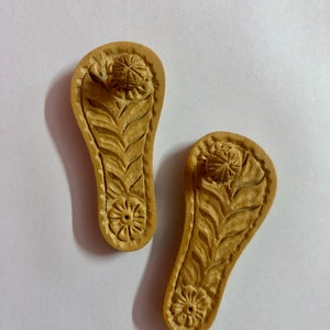 Pu&ograve; includere: Due porta incensi in legno a forma di sandali con intricate sculture di fiori e foglie. I supporti hanno un piccolo foro nella parte superiore per i bastoncini di incenso.