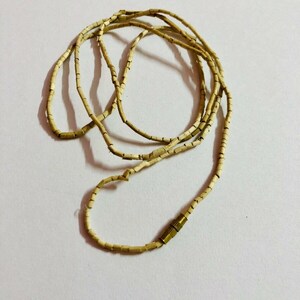 May include: A beige necklace made of small, rectangular beads with a gold clasp.