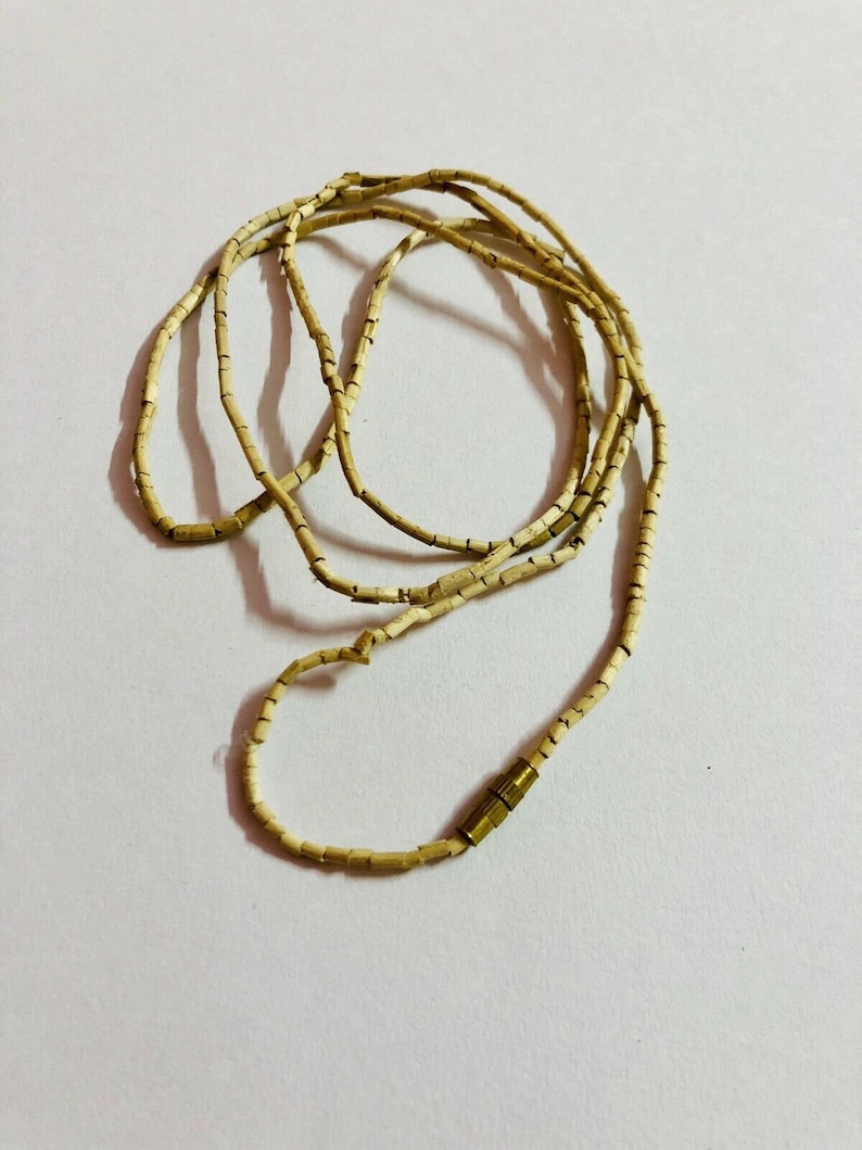 May include: A beige necklace made of small, rectangular beads with a gold clasp.