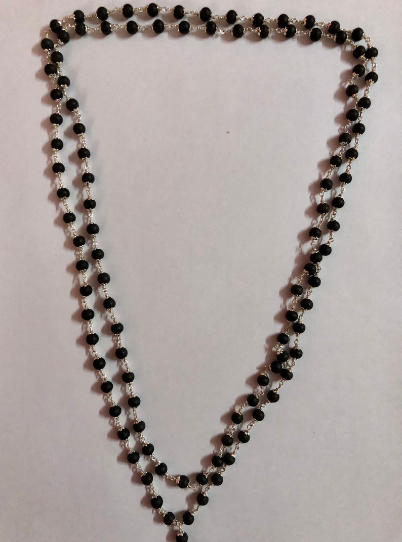 May include: A black beaded necklace with a silver chain. The necklace is made of round beads and is approximately 18 inches long.