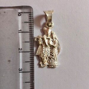 Op de afbeelding: Zilveren hanger met een gedetailleerde afbeelding van Radha Krishna, een hindoe&iuml;stisch godenpaar, dat samen staat. De hanger is ongeveer 5 cm hoog en perfect voor een ketting of een bedelarmband.