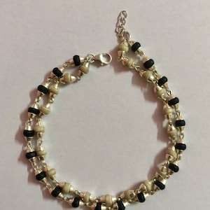 May include: A silver bracelet with black and white beads. The bracelet has a clasp fastening.