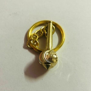 May include: A gold-coloured keychain with a decorative, swirling, pointed ball attached to a ring and chain.