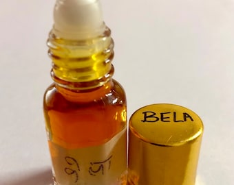 May include: A small, clear glass bottle with a gold cap and a white roller ball. The bottle contains a brown liquid and has a label with the word "BELA" and the text "बेल" in Hindi.