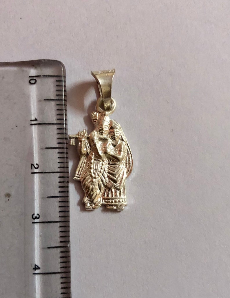 Op de afbeelding: Zilveren hanger met een gedetailleerde afbeelding van Radha Krishna, een hindoe&iuml;stisch godenpaar, waarbij Radha een fluit vasthoudt. De hanger is ongeveer 5 cm hoog.