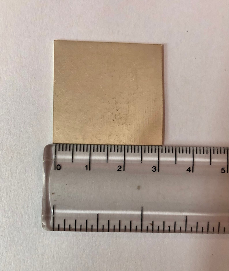 May include: A gold-colored metal sheet measuring approximately 3 inches by 3 inches.