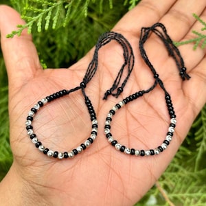 May include: Two black and silver beaded bracelets with adjustable string closures.