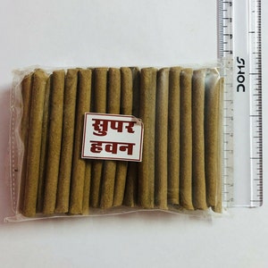 May include: A clear plastic bag filled with brown sticks labelled "सुपर हवन" (Super Havan).