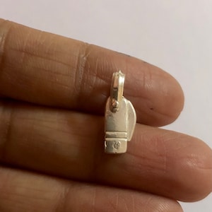 May include: Silver charm in the shape of a small, detailed, vintage-style iron. The charm has a loop at the top for attaching to a necklace or bracelet.