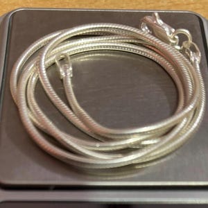 Pode incluir: Um colar de corrente de cobra de prata com fecho de lagosta.