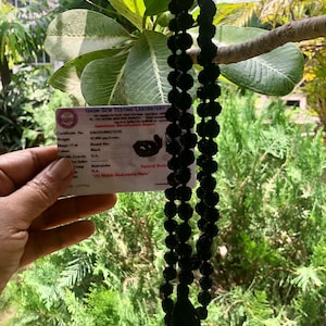 May include: A black Rudraksha Mala with a tassel, a string of beads used in Hinduism and Buddhism for prayer and meditation. The mala is 42 grams and is made of 5 Mukhi Rudraksha beads. The certificate of authenticity is visible in the image.