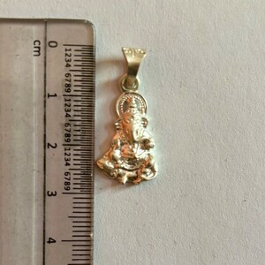 May include: Silver pendant featuring a detailed depiction of the Hindu deity Ganesha. The pendant is approximately 2 cm in height and is ready to be added to a necklace or chain.