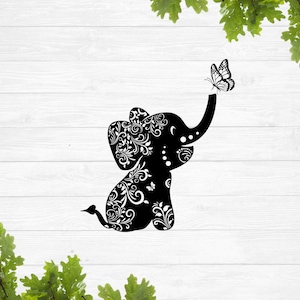 May include: Black silhouette of a stylised elephant with intricate floral patterns. The elephant's trunk is raised and a butterfly is perched on the end of it.
