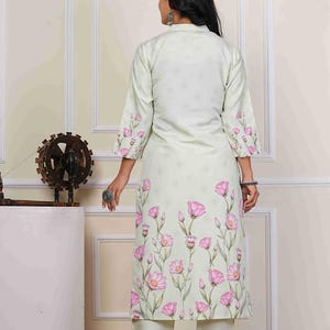 May include: A light green floral print kurta and matching pants set. The long-sleeved kurta features a high collar and is adorned with pink flower designs. The pants are a solid light green color. The outfit is suitable for casual or semi-formal occasions.
