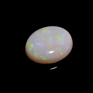 以下が含まれることがあります： 緑と青の虹色の輝きを持つ白いオパール宝石。オパールは楕円形で、滑らかで磨かれた表面をしています。