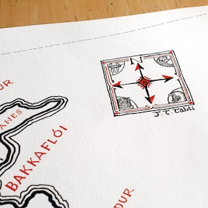 May include: A white paper map featuring black and red ink illustrations. The map displays the text Langanes, Bakkafl&oacute;i, and Gylfj&ouml;r&eth;ur in red. A square compass rose with red and black arrows and the text J.T. Tabti is visible.