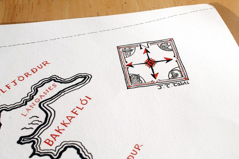 May include: A white paper map featuring black and red ink illustrations. The map displays the text Langanes, Bakkafl&oacute;i, and Gylfj&ouml;r&eth;ur in red. A square compass rose with red and black arrows and the text J.T. Tabti is visible.