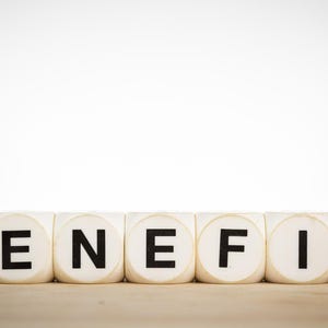 May include: A conceptual image featuring the word "BENEFIT" spelled out with white letter blocks. A blue game piece sits atop the "B", and a red game piece sits atop the "T". The background is white.