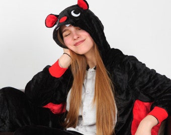 May include: A black and red plush animal onesie with a mouse head. The onesie has a hood with a black nose and red ears. The person wearing the onesie has long, straight, red hair.