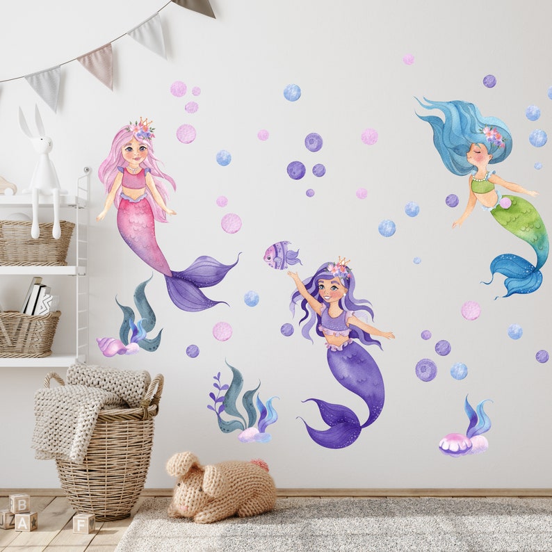 May include: Three watercolor mermaid wall decals with purple, pink, and blue tails. The mermaids are surrounded by pink and blue bubbles.
