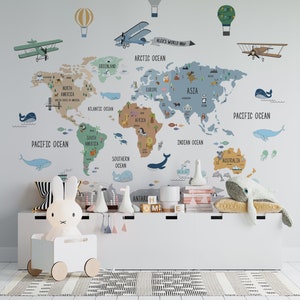 May include: A colorful world map wall decal with illustrations of animals, airplanes, hot air balloons, and whales. The map is on a light blue wall with a white shelf below it. The shelf has a white bunny nightlight, a white whale stuffed animal, and other decorative items.