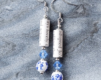 May include: A pair of silver dangle earrings with blue and white porcelain beads and a rolled up piece of paper with the text "adopted Jo's calling the ways lovely t and actors a"