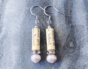 May include: A pair of dangle earrings with a silver hook and a white cylinder charm with black text that reads "Sweet girl, Miss Bennet" and "Matter as we indeed". Each charm is topped with a clear rhinestone and a pink pearl.