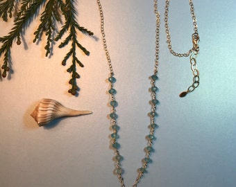 Necklace in blue chalcedony rondelles on rosary chain hang over a faceted oval  blue sapphire.