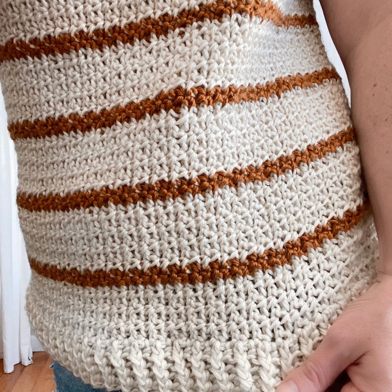 May include: Close-up of a crocheted top with horizontal stripes in white and brown.