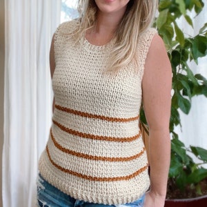 May include: A sleeveless crochet top with brown stripes. The top is made with a white yarn and has a loose, relaxed fit.
