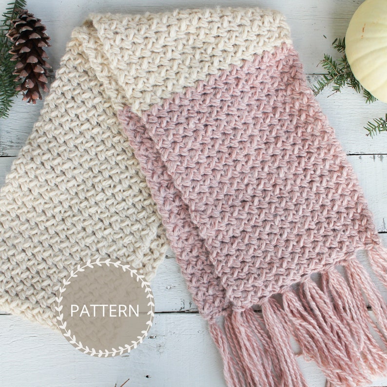 K&ouml;nnte beinhalten: Ein gestrickter Schal mit einem Farbverlauf von Creme zu Rosa. Der Schal hat Fransen an den Enden und das Wort "PATTERN" steht auf einem Kreis im Bild.