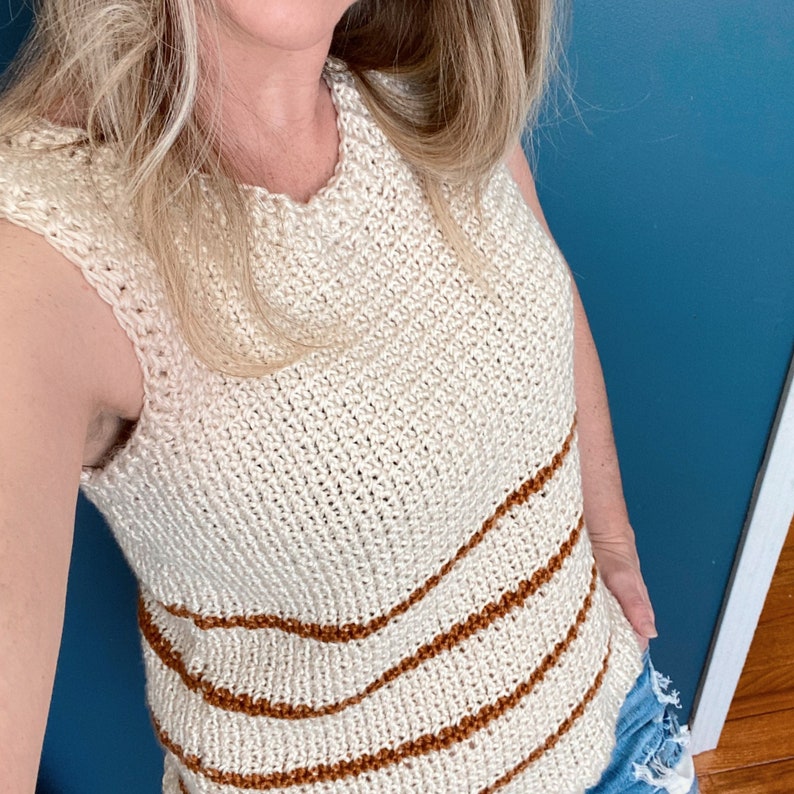 May include: A white crochet tank top with brown stripes. The tank top has a scoop neck and sleeveless design.