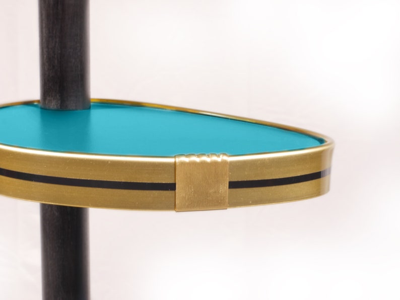 Op de afbeelding: Een turquoise plank met een gouden rand en een zwarte streep. De plank is bevestigd aan een zwarte paal.