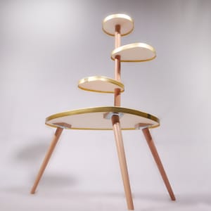 Op de afbeelding: Een gouden en houten etag&egrave;re met vier ronde planken. De etag&egrave;re heeft een modern ontwerp en is perfect om planten of andere decoratieve items te presenteren.