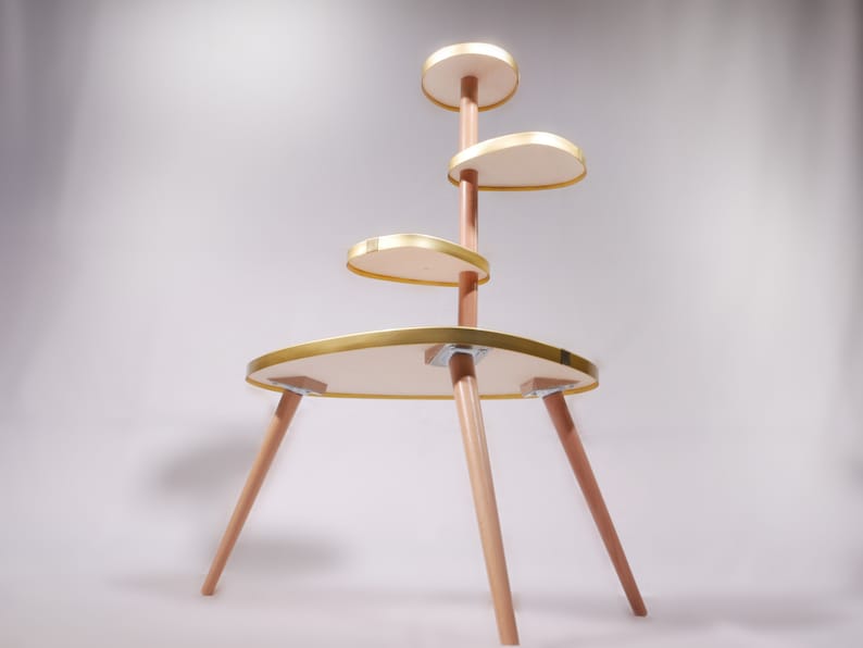 Op de afbeelding: Een gouden en houten etag&egrave;re met vier ronde planken. De etag&egrave;re heeft een modern ontwerp en is perfect om planten of andere decoratieve items te presenteren.