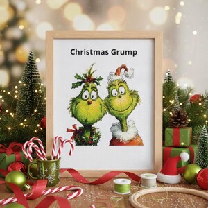 May include: A framed cross-stitch featuring two green cartoon characters with the text "Christmas Grump". The image is surrounded by Christmas decorations, including candy canes, ornaments, and a small Santa hat.