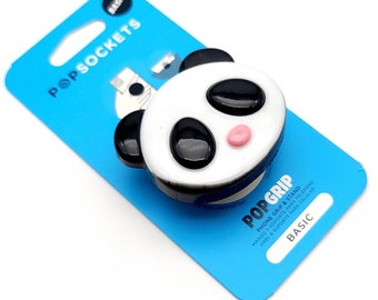 May include: A white and black panda phone grip and stand with a pink nose. The grip is labelled "PopGrip" and "Basic".