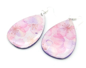 May include: A pair of teardrop-shaped earrings with a pink and purple floral pattern. The earrings have silver hooks.