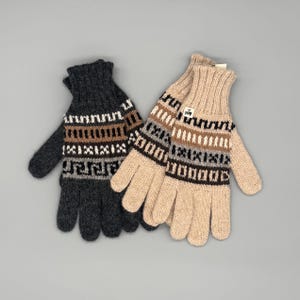 Könnte beinhalten: Zwei Paar Strickhandschuhe. Ein Paar ist dunkelgrau mit braunen, weißen und schwarzen geometrischen Mustern. Das andere Paar ist beige mit ähnlichen Mustern. Beide haben ein Etikett.