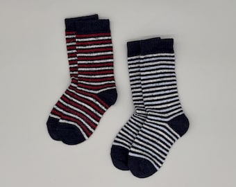 May include: Two pairs of mid-calf socks. One pair features horizontal stripes in navy blue, white, and red. The second pair features horizontal stripes in navy blue and white. Both pairs have solid navy blue toes, heels, and cuffs with a ribbed texture.