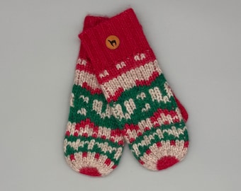 May include: A pair of knit mittens featuring a red, green, and cream-colored geometric pattern. The cuffs are solid red with a small, circular brown leather patch embossed with a black llama silhouette centered on the top cuff.