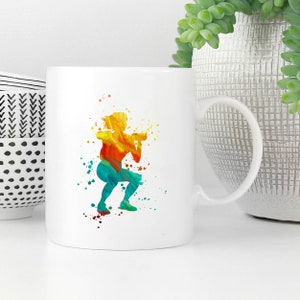 May include: White ceramic mug with a colorful silhouette of a person doing a squat exercise. The silhouette is made up of yellow, orange, red, green, and blue watercolor-like paint splatters.