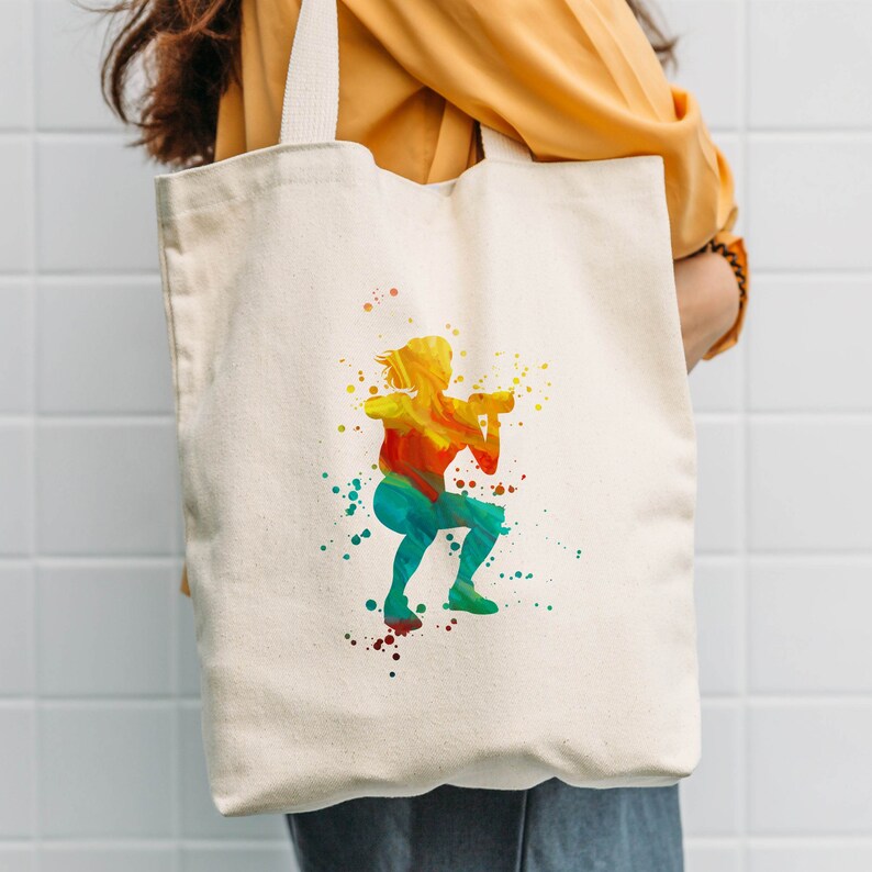 May include: A white canvas tote bag with a colorful watercolor silhouette of a person lifting weights. The silhouette is in shades of yellow, orange, red, green, and blue.