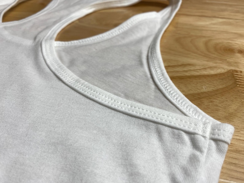 Op de afbeelding: Wit tanktop met racerback-stijl en een dubbele gestikte halslijn.