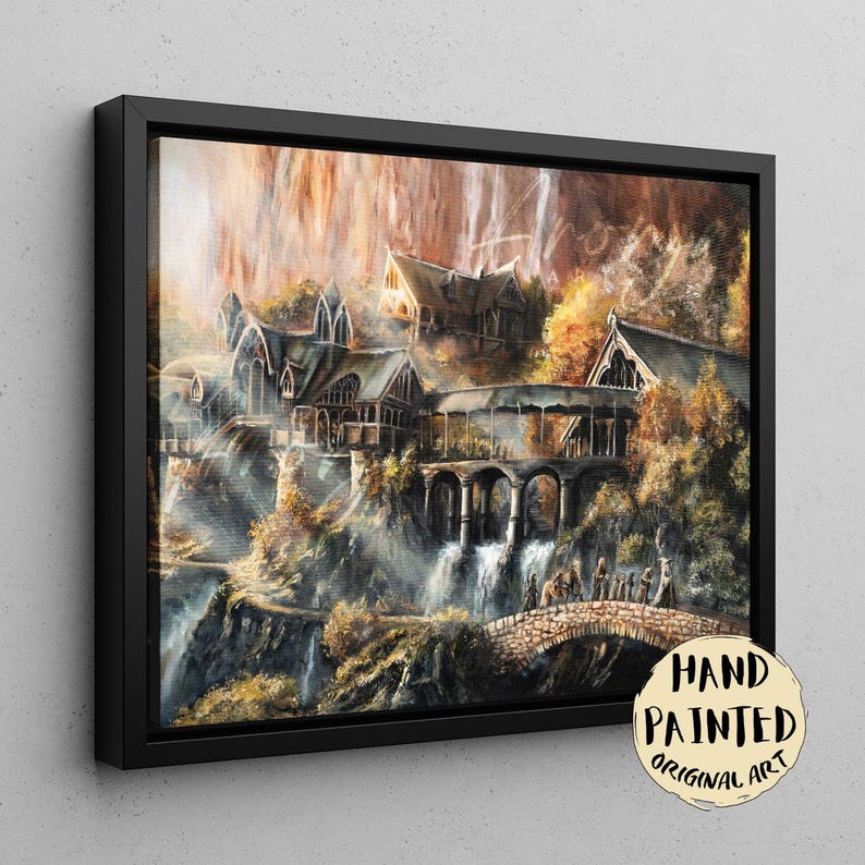 Op de afbeelding: Een ingelijste canvasprint met een gedetailleerd schilderij van een fantasienederzetting met puntdaken, stenen bogen en watervallen die langs kliffen naar beneden stromen. Een stenen brug overspant de voorgrond met kleine figuren. Tekst: HAND PAINTED ORIGINAL ART.